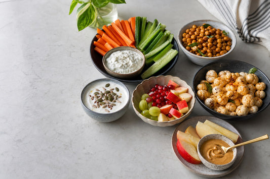 Portioned healthy Indian snacks with fruit, curd, roasted chana, vegetables and peanut butter
